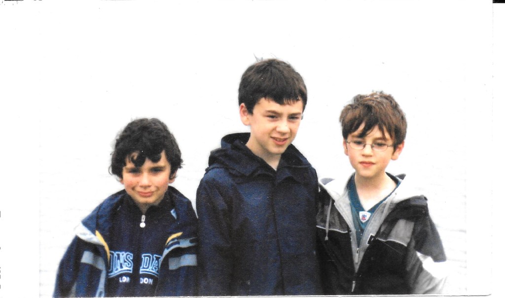 Three young boys, all in navy blue anoraks.