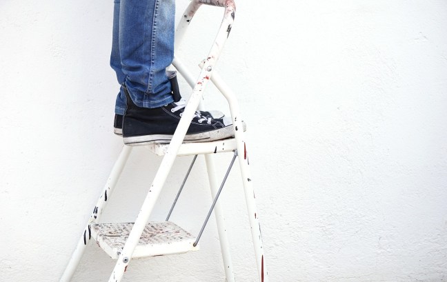 The ankles and feet of someone on a painter's ladder