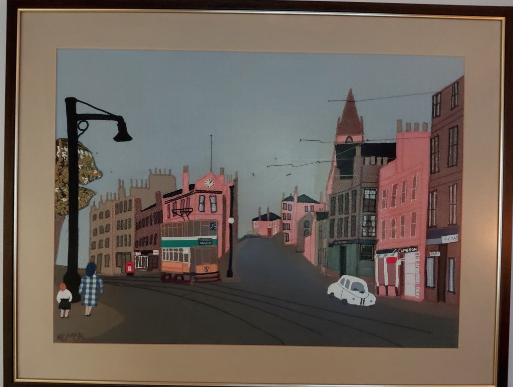 A fabric collage interpretation showing a Springburn street junction with tenements, a tram and a white car. Two people in bottom left corner - it was too fiddly to add the many people in the original photo!