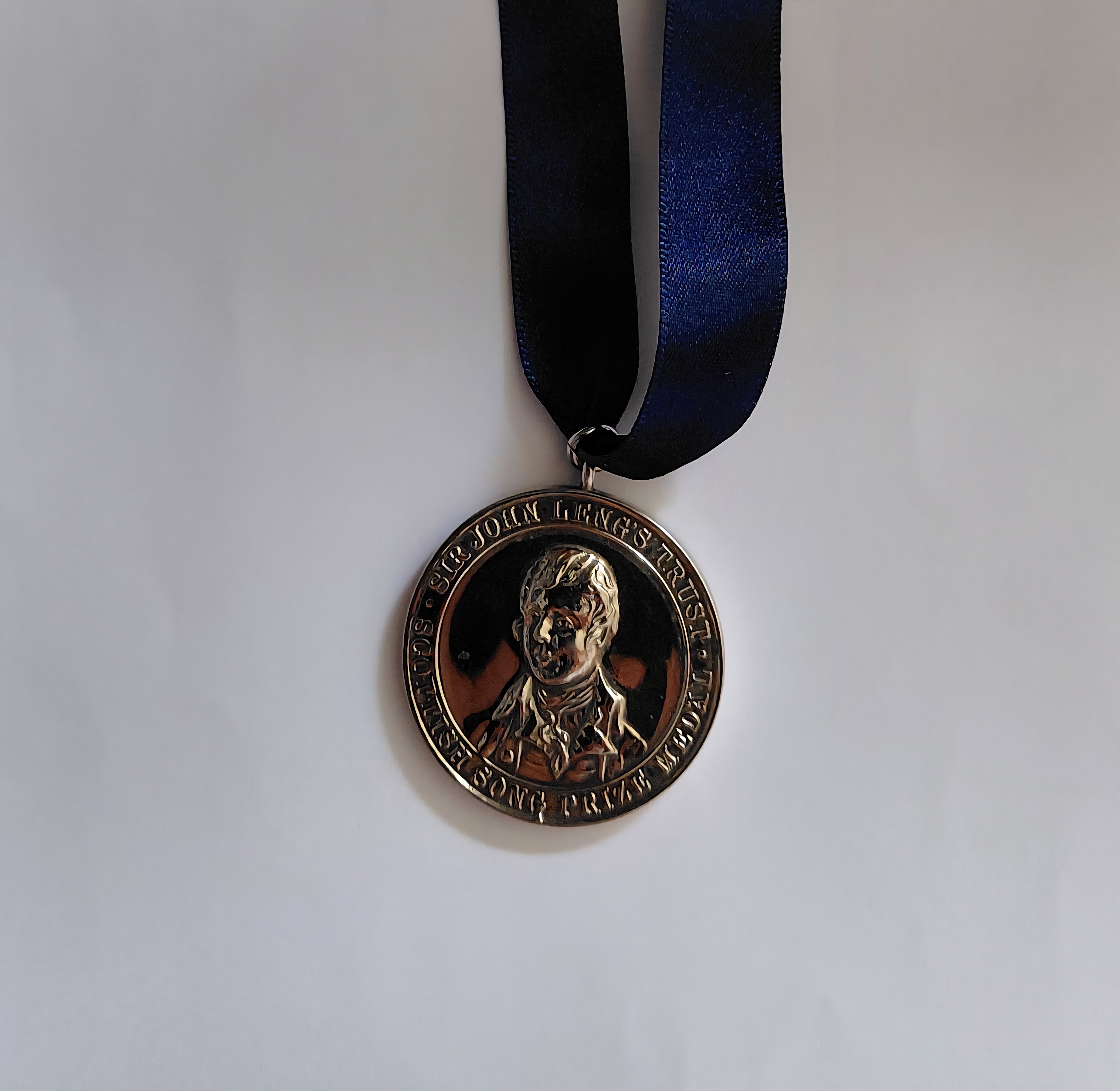 A silver Leng Medal for Scots Song, on a blue ribbon